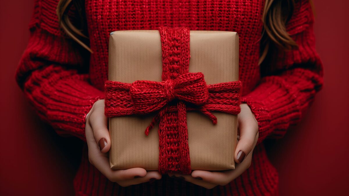 58789188 a woman in a red tartan scarf holds a woolen gift with a magenta bow