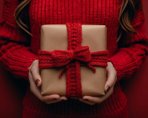 58789188 a woman in a red tartan scarf holds a woolen gift with a magenta bow
