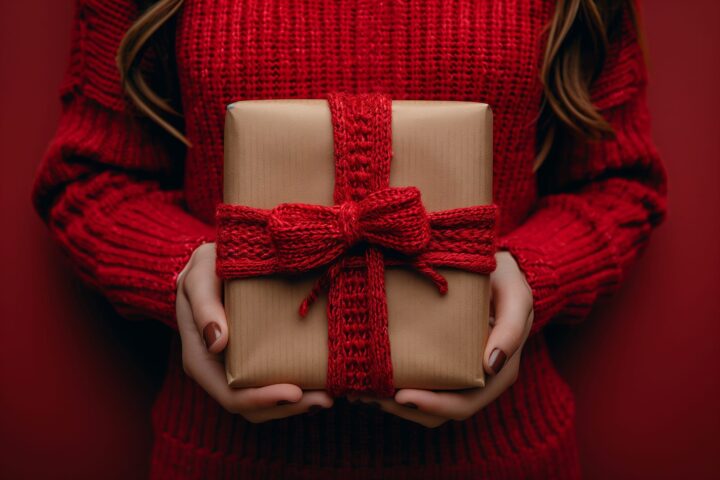 58789188 a woman in a red tartan scarf holds a woolen gift with a magenta bow