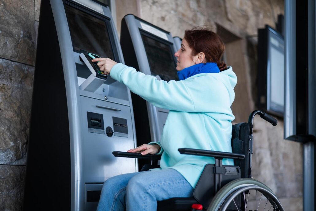 Caucasian woman in a wheelchair buys a train ticket using a mobile phone at a self service checkout