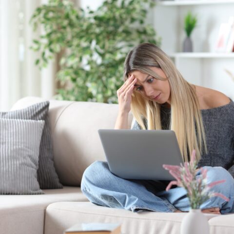 101064324 worried woman on a sofa checking personal computer