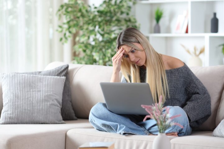 101064324 worried woman on a sofa checking personal computer