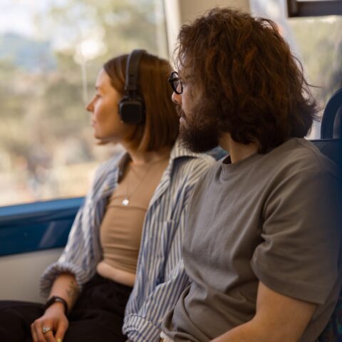 56621078 handsome tourist couple is travel together while riding in public bus and looking at window